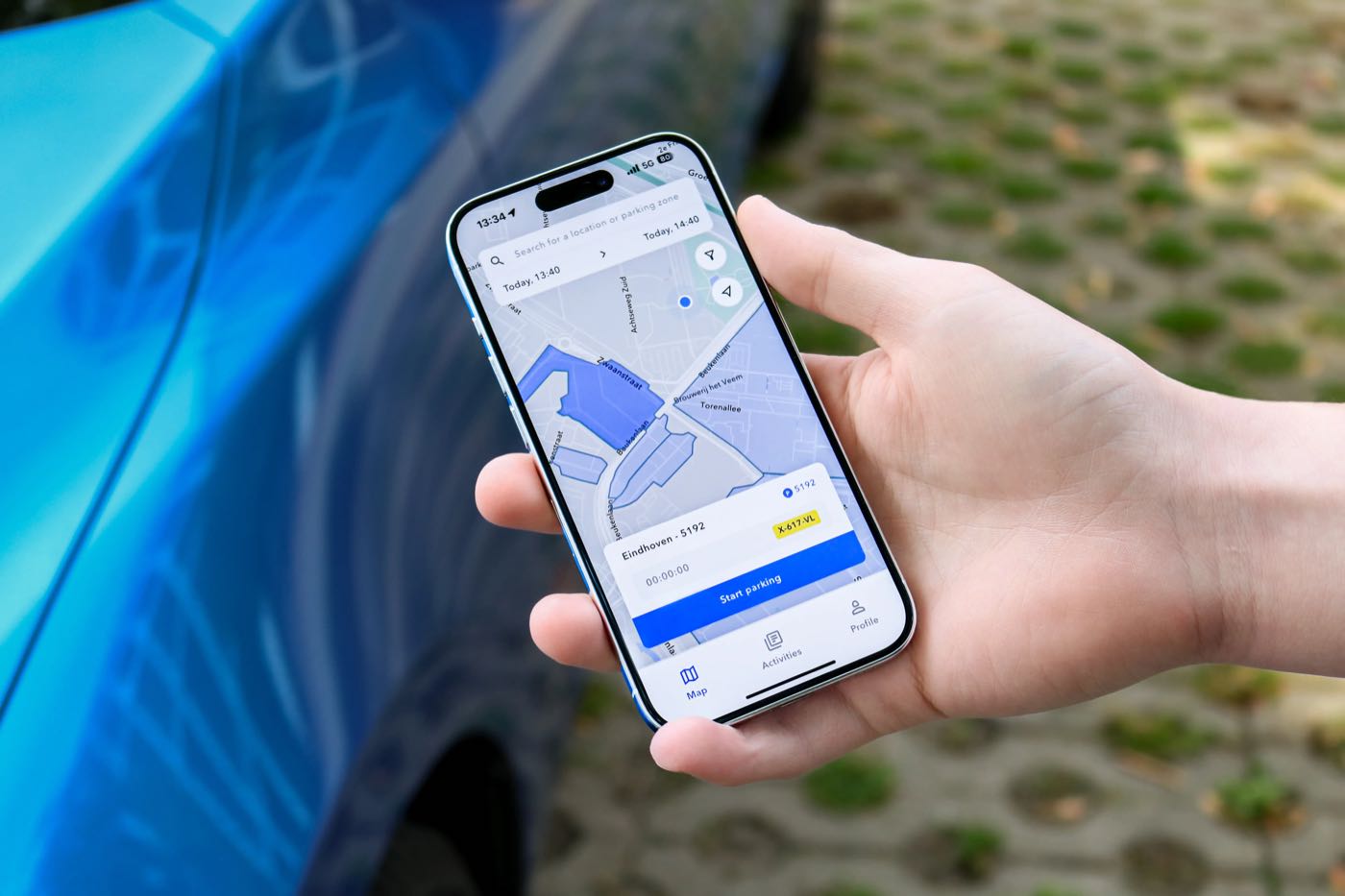 A hand holding a phone with the SimplePark app next to a car