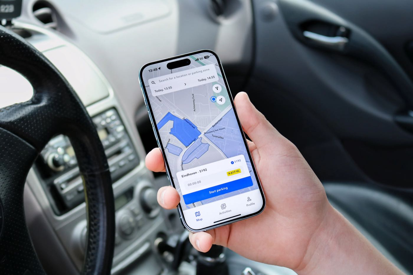 A hand holding a phone with the SimplePark map inside a car